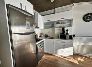 cocina con armarios blancos y nevera de acero inoxidable en Bosphorus Seaview flat & Alexa smart home by SUMMITVISTA, en Estambul