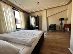 1 dormitorio con 1 cama blanca grande y 1 silla en Bosphorus Seaview flat & Alexa smart home by SUMMITVISTA, en Estambul