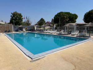 a large blue swimming pool with lounge chairs in a yard at Mobil Home avec spacieuse terrasse à Meschers proche de Royan in Meschers-sur-Gironde +9 photos