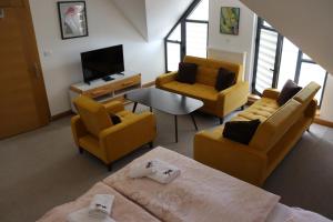 uma sala de estar com mobiliário amarelo e uma televisão em Apartmani Vlašić-Petrol em Travnik