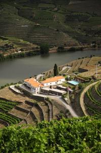 a building on a hill next to a river at Hotel Rural Quinta Do Pego in Tabuaço