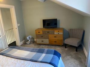 a bedroom with a dresser with a tv and a chair at Victorian South Belfast area Lisburn Road 3 Double Bedrooms - Great Transport Links in Belfast