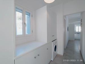 a white laundry room with a window and a washing machine at George's Seaside Apartments Sifnos in Vathi