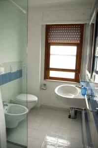 een badkamer met een wastafel en een toilet en een raam bij Casa delle Palme sulla spiaggia in Marzamemi