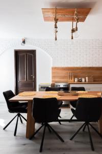 uma cozinha com uma mesa de madeira e cadeiras pretas em Ligeti Bástya Vendégház 