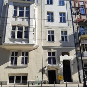 un edificio blanco con ventanas negras en una calle de la ciudad en Apartament u Olechny 4 en Bydgoszcz