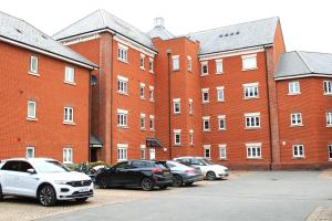 a group of cars parked in front of a large brick building at Luxury Apartment Close to Town Centre in Lexden