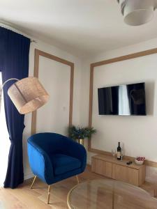 sala de estar con silla azul y TV en Lungomare Apartments, en Petrovac na Moru