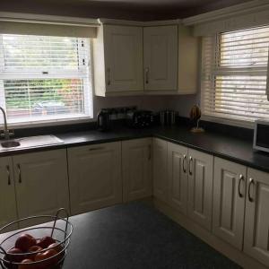 a kitchen with white cabinets and a bowl of fruit at Harbour View House in Ballycastle