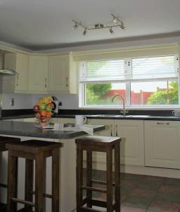 a kitchen with a sink and a counter with stools at Harbour View House in Ballycastle