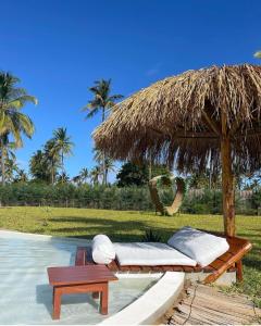 a bed with a straw umbrella and a table at Casa Bali Tofo in Praia do Tofo