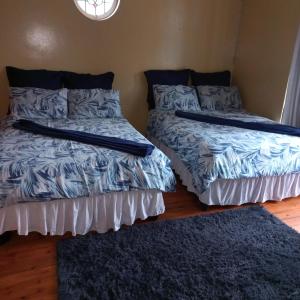a bedroom with two beds with pillows and a rug at Alo guesthouse in Pietermaritzburg