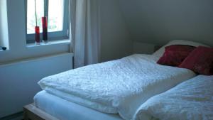 Bett mit weißer Bettwäsche und roten Kissen neben einem Fenster in der Unterkunft Casa Manfredi in Prerow