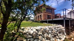 una casa en la cima de una colina con una pared de piedra en La Ñata en Villa Giardino
