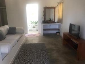a living room with a couch and a tv at Casa Bali Tofo in Praia do Tofo