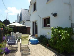 patio z 2 krzesłami i parasolem w obiekcie Maison 3 chambres 250 m de la mer w mieście Trinité-sur-Mer
