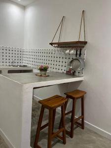 a kitchen with a counter with a sink and two stools at Casa Bali Tofo in Praia do Tofo