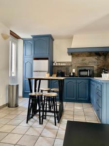 une cuisine avec des placards bleus, une table et des tabourets dans l'établissement T2 rue piétonne Le Lavandou climatisé, au Lavandou