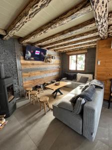 ein Wohnzimmer mit einer Couch, einem Tisch und einem Fernseher in der Unterkunft Chalet Les Sapins sauna au pied des pistes in La Bresse