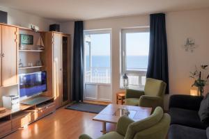 een woonkamer met een bank, een televisie en een tafel bij Nordland Appartements - Wohnung Amrum in Wyk auf Föhr