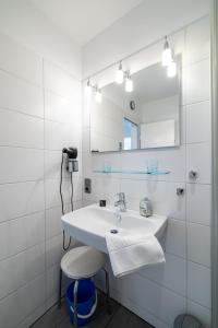 een badkamer met een wastafel, een spiegel en een kruk bij Nordland Appartements - Wohnung Amrum in Wyk auf Föhr