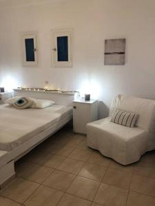 a white room with a bed and a chair at Beach House in Ios Cyclades in Tzamaria