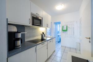 een witte keuken met een wastafel en een magnetron bij Nordland Appartements - Wohnung Hooge in Wyk auf Föhr