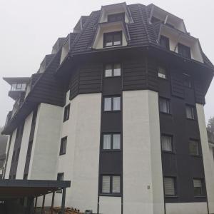 a tall black and white building with a roof at Kai Apartman in Kopaonik