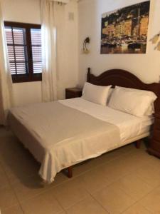 a bedroom with a bed with white sheets and a window at VILLA ANGELINA in Playa Blanca
