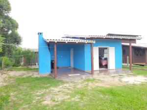 una pequeña casa azul en un patio en Casa temporada praia da galheta 3, en Laguna