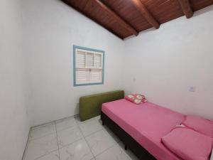 1 dormitorio con cama rosa y ventana en Casa temporada praia da galheta 3 en Laguna