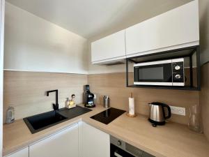 a kitchen with a sink and a microwave at L'intemporel plage - Malo'Cation in Dunkerque