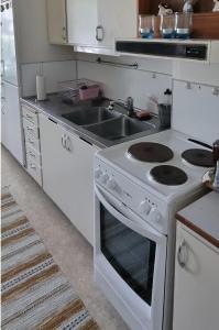 a white kitchen with a stove and a sink at Mysig Lägenhet för resande. in Stocka