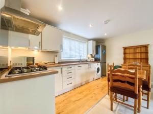 een keuken met witte kasten en een tafel en stoelen bij Peacock Court in Corsham