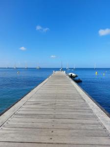 a wooden pier in the middle of the water with boats at T2 cirique in Les Anses-dʼArlets