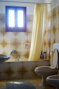 a bathroom with a yellow shower curtain and a toilet at Traditional cozy residence in Lafkos, Pelion in Lafkos