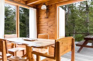 - une table et des chaises en bois sur la terrasse couverte d'une cabine dans l'établissement BOG Ocrehue - Cabanas, à Villa La Angostura