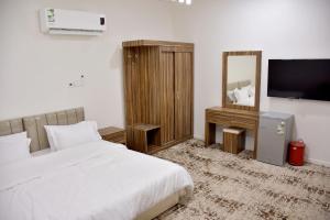 a bedroom with a bed and a mirror and a television at فندق الجوافة in Najran