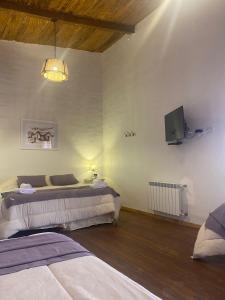 a bedroom with two beds and a tv on the wall at Hostería La Celestina in Tilcara