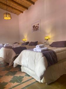 a room with three beds with towels on them at Hostería La Celestina in Tilcara