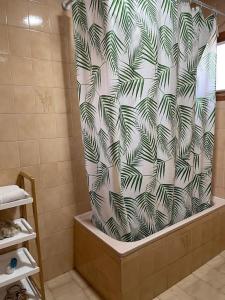 een douchegordijn met een palmboompatroon in de badkamer bij El rincón del cabo! in Almería