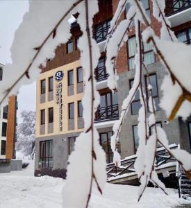 Un edificio con un árbol cubierto de nieve delante. en Park residence, en Bakuriani