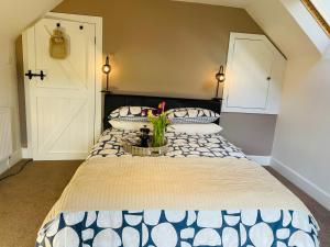 a bedroom with a large bed with a vase of flowers on it at Coachmans Cottage in Aberlour