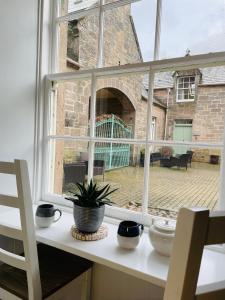 a window with a potted plant sitting on a counter at Coachmans Cottage in Aberlour
