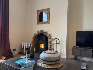 a living room with a fireplace and a table with wine glasses at Coachmans Cottage in Aberlour