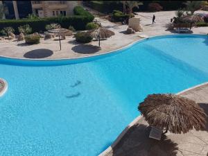 uma grande piscina azul com guarda-sóis de palha em Palma Resort Hurghda em Hurghada