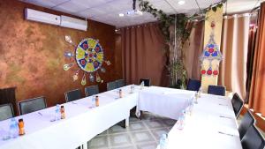 uma sala de reuniões com mesas e cadeiras brancas e uma parede em hotel brahimi batna em Batna