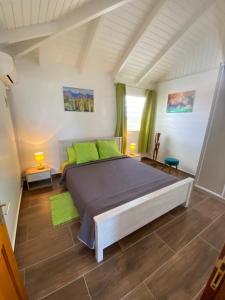 una camera da letto con un grande letto con cuscini verdi di Villa Papillon a Saint-François