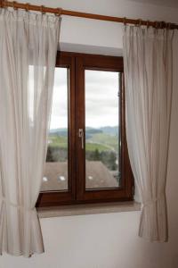una ventana con cortinas blancas en una habitación en Ferienwohnung im Allgäu mit Bergsicht en Oberreute