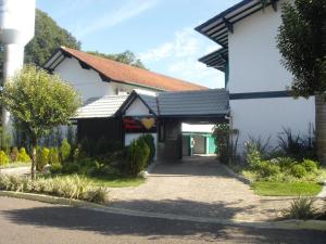 a white and black building with a driveway at Motel Avenida (Adult Only) in Gramado